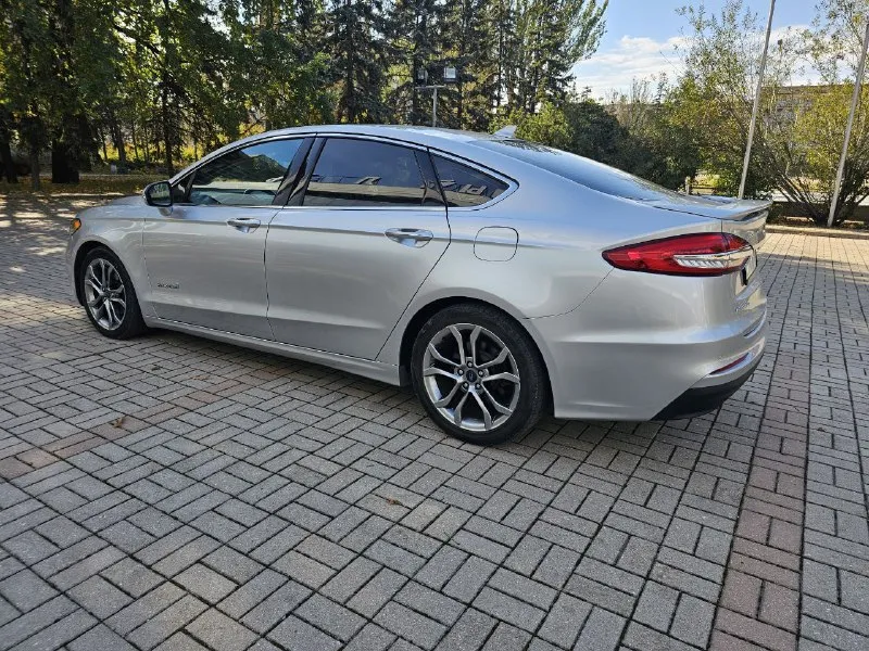 Ford fusion hybrid 2019 titanium (usa) американский mondeo в топовой комплектации! пробег 99 800 км 🔋 гибрид — расход 5–6 л/100 км, на баке до 900 км пробега. 🔧 полностью обслужен, без сюрпризов. 💪надёжный — такие фьюжены в сша проходят 500 000+ км без проблем. ❗первый владелец в рф, подбирал и пригонял под себя. 💎 titanium: адаптивный круиз, удержание в полосе, автоторможение, контроль слепых зон, full led фары, камера, парктроники, кожа, вентиляция и подогрев сидений, подогрев руля, аудио sony, бесключевой доступ, дистанционный запуск, кодовый вход, настраиваемая подсветка, еврозеркала (!) с широким обзором и складыванием. 📌 пробег оригинальный, любая проверка. 💬 без посредников. 📍 осмотр и тест-драйв в донецке 💸 1 890 000 ₽ +79494710689 - фотография - 3