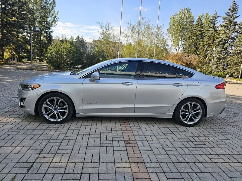 Ford fusion hybrid 2019 titanium (usa) американский mondeo в топовой комплектации! пробег 99 800 км 🔋 гибрид — расход 5–6 л/100 км, на баке до 900 км пробега. 🔧 полностью обслужен, без сюрпризов. 💪надёжный — такие фьюжены в сша проходят 500 000+ км без проблем. ❗первый владелец в рф, подбирал и пригонял под себя. 💎 titanium: адаптивный круиз, удержание в полосе, автоторможение, контроль слепых зон, full led фары, камера, парктроники, кожа, вентиляция и подогрев сидений, подогрев руля, аудио sony, бесключевой доступ, дистанционный запуск, кодовый вход, настраиваемая подсветка, еврозеркала (!) с широким обзором и складыванием. 📌 пробег оригинальный, любая проверка. 💬 без посредников. 📍 осмотр и тест-драйв в донецке 💸 1 890 000 ₽ +79494710689 - фотография - 4