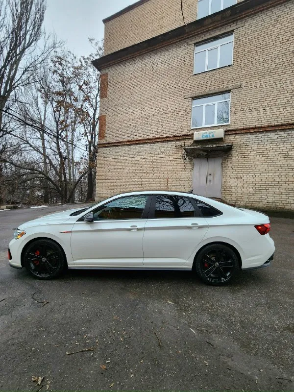 Предлагаю вам заряженную версию в максимальной комплектации vоlkswаgеn jеttа 2.0 gli аutоbаhn 2022 года рест в отличном, состоянии, без дефектов! пробег 90т. км. jеttа gli оснащен панорамным люком на 2/3 крыши, что добавляет салону света и воздуха. мультифункциональный сенсорный руль с поддержкой жестового управления делает взаимодействие с автомобилем еще более удобным и современным. рестайлинг 2022: обновленный дизайн, улучшенная мультимедийная система и дополнительные опции безопасности делают эту модель еще привлекательнее. полный заводской экстерьер. комплектация: максимальная. цвет: oryx white metallic. jetta gli autobahn - эта эксклюзивная комплектация включает: 18-дюймовые черные легкосплавные диски с летними шинами pirelli p zero, зимним michelin x-ice snow липучка 235/45r18. черную крышу. - черные корпуса боковых зеркал. черный спойлер на крышке багажника. основные технические характеристики: двигатель: 2.0-литровый турбированный тsi (еа888 gеn3) мощностью 231 📞 звоните: +7(949)0836253 - фотография - 4